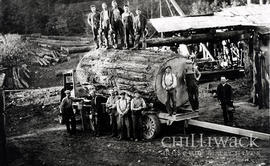 Group portrait of men posing with huge fir log loaded on truck at the Orion Bowman mill